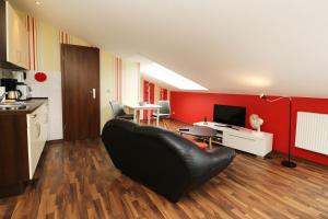ein Wohnzimmer mit einem schwarzen Ledersofa und roten Wänden in der Unterkunft Ferienhaus Quartier18 strandnah S2 in Ostseebad Karlshagen