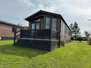 a small house with a large deck on the grass at Meadow View Lodge at Hollin Barn Lodge park Thirsk,North Yorks in Thirsk