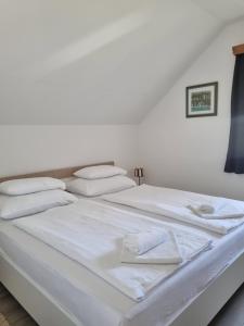a large white bed with white sheets and pillows at Apartment Rosandić in Smoljanac