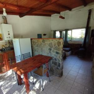 a kitchen with a wooden table and a stone wall at Complejo Cerro Norte in Piedras Blancas
