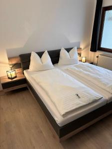 ein großes Bett mit weißer Bettwäsche und Kissen darauf in der Unterkunft Ferienwohnung K38 in Eisenach