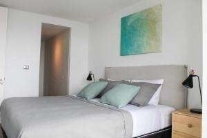 a bedroom with a white bed with two blue pillows at Amplio Depto 2D2B Estacionamiento y Terraza Vista al Mar Servicio HOM in Antofagasta