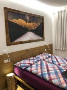 - une chambre dotée d'un lit avec une photo sur le mur dans l'établissement Casa Volcan, à Tesero