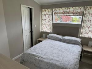 a small bedroom with a bed and two windows at Meadow View Lodge at Hollin Barn Lodge park Thirsk,North Yorks in Thirsk