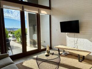 Una sala de estar con un televisor, un sofá y una mesa. en HOM I Amplio Loft con Jardín en MejorLugar de Valparaíso 1109, en Valparaíso