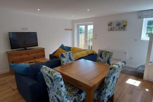 een woonkamer met een blauwe bank en een houten tafel bij Pond Puddle at Pond Pool Cottage in Taunton