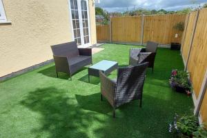 een patio met stoelen en een tafel op het gras bij Pond Puddle at Pond Pool Cottage in Taunton