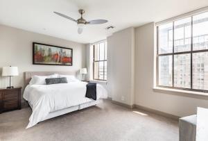 a white bedroom with a bed and two windows at 2BR Luxury Apartment With Rooftop Deck & Pool in Baltimore