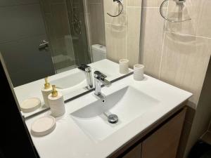 La salle de bains est pourvue d'un lavabo blanc et d'un miroir. dans l'établissement ENCANTADOR Depto en la Mejor Ubicación de PtoVaras, à Puerto Varas