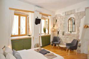 a bedroom with a bed and two chairs and a stone wall at Charming apartment in Kotor in Kotor