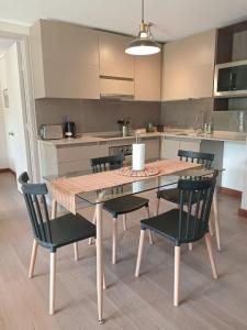 a kitchen with a wooden table with chairs and a kitchen with a counter at Amplio Depto de 2 dormitorios Frente al Lago y Parking Servicio HOM in Puerto Varas