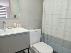 a white bathroom with a toilet and a sink at Amplio Depto de 2 dormitorios Frente al Lago y Parking Servicio HOM in Puerto Varas
