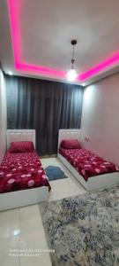 two beds in a room with pink lighting at Mansbay beach in Aïn Harrouda