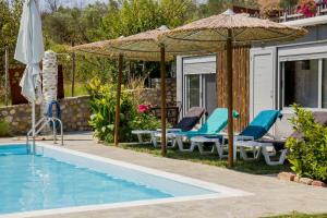 a pool with chairs and umbrellas next to a house at Attalos Mythical Nest - Private Pool Escapade in Tsáyezi
