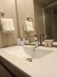 y baño con lavabo blanco y espejo. en Cómodo Depto Nuevo en la Mejor Zona de Pto Varas Servicio HOM, en Puerto Varas
