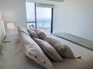 a row of pillows on a bed with a window at Dúplex con Terraza y Parking con vista al MarHOM 1118 in Antofagasta