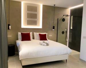 une chambre avec un grand lit blanc avec des oreillers rouges dans l'établissement Su Coru 2 - Deluxe Studio in the Heart of Cagliari, à Cagliari