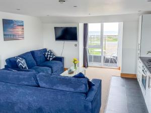 Waves Guest Suites في كاستل: غرفة معيشة بها أريكة زرقاء وتلفزيون