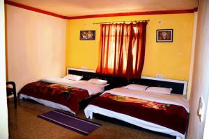 twee bedden in een kamer met gele muren bij Badrinath Guest House in Badrīnāth