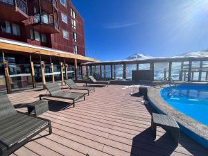 a deck with chairs and a swimming pool on a building at Edif Mirador del Inca Espectacular Loft En Valle Nevado 10PAX Piscina in Lo Barnechea