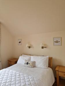 1 dormitorio con 1 cama con sábanas y almohadas blancas en Lodges at the Mains, en Inverness