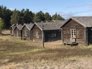 Ulvöhamn的住宿－Sandvikens Fiskeläge Ulvön，田野上一排古老的木结构建筑
