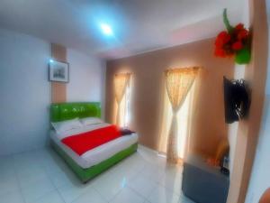 a bedroom with a bed and a television in it at BOTANIA HOMESTAY BATAM in Nongsa