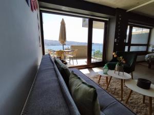 - un salon avec un canapé bleu et une grande fenêtre dans l'établissement Acogedor 2D2B, En Cerro Barón con estacionamiento Servicio HOM, à Valparaíso