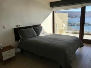 - une chambre avec un grand lit et une grande fenêtre dans l'établissement AMPLIO 4D3B Mejor ubicación Valparaíso Parking 6PAX Servicio HOM, à Valparaíso