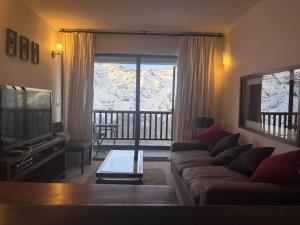 a living room with a couch and a large window at Edif Valle de Cóndores II AmplioDúplex 6PAX SKIOUT Servicio HOM in Farellones