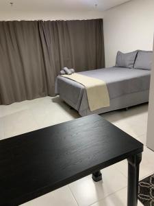 a room with two beds and a black table at Inova Flat aconchego no Condominio Cosmopolitan in Palmas
