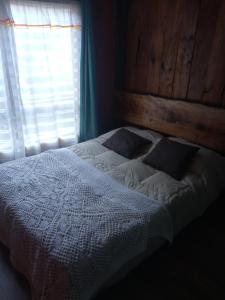 a bedroom with a bed with a wooden headboard and a window at hostal Coñaripe in Panguipulli