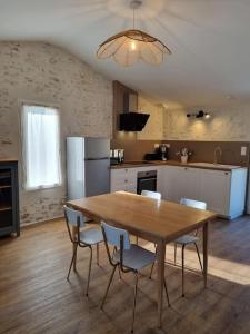 een keuken met een houten tafel en stoelen. bij O Pressoir in Le Pellerin