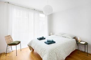een witte slaapkamer met een bed en een stoel bij Nouveau - Harmonia in Nantes
