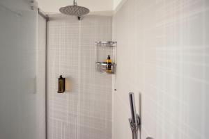 y baño con ducha y paredes de azulejos blancos. en Appartamenti La Grotta, en Bardolino