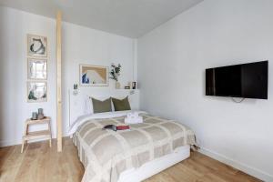 a white bedroom with a bed and a flat screen tv at Jardin des Plantes - Studio - CityApartmentStay in Paris