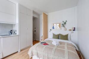 a white bedroom with a bed and a kitchen at Jardin des Plantes - Studio - CityApartmentStay in Paris
