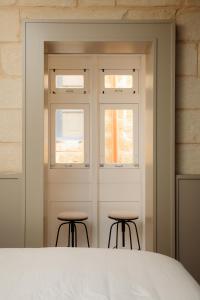 a bedroom with a white door and two stools at Domingo x Casa Norte in Birgu