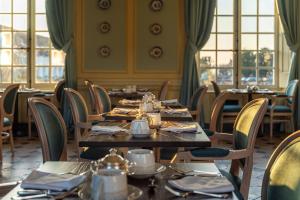 un comedor con mesas, sillas y ventanas en Le Château D'Etoges, en Étoges