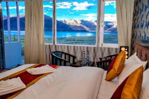 a bedroom with a bed with a view of the mountains at The Pangong Heights Cottages in Leh