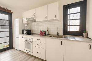a kitchen with white cabinets and a sink and a window at Los Cardones Boutique Village in Playa de las Americas
