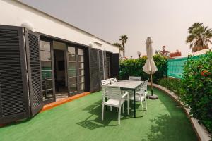 a patio with a table and chairs and an umbrella at Los Cardones Boutique Village in Playa de las Americas