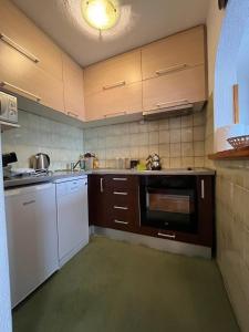 eine Küche mit weißen Geräten und braunen Schränken in der Unterkunft Guesthouse Vratnik in Sarajevo