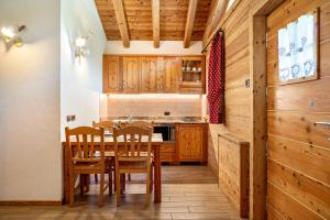 a kitchen with wooden cabinets and a table and chairs at Chalet Camping Faè 8 - Trilocale in Madonna di Campiglio