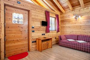 a living room with a couch and a tv in a log cabin at Chalet Camping Faè 8 - Trilocale in Madonna di Campiglio