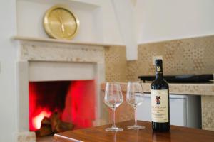 - une bouteille de vin assise sur une table avec 2 verres à vin dans l'établissement Suite Votano 24 - RELAX nel CUORE ANTICO di CEGLIE, à Ceglie Messapica