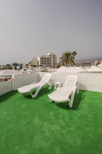 twee witte ligstoelen op een dak met groen gras bij Los Cardones Boutique Village in Playa de las Americas