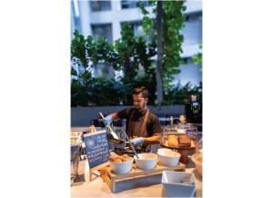 a man in an apron preparing food on a table at Ceylonz Suites KL Tower View Bukit Bintang in Kuala Lumpur
