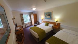 a hotel room with two beds and a desk at Alton House Hotel in Alton