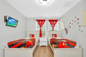 two twin beds in a bedroom with red curtains at Roomy Town Home, Mickey-Themed Bedroom! #4BV550 in Kissimmee